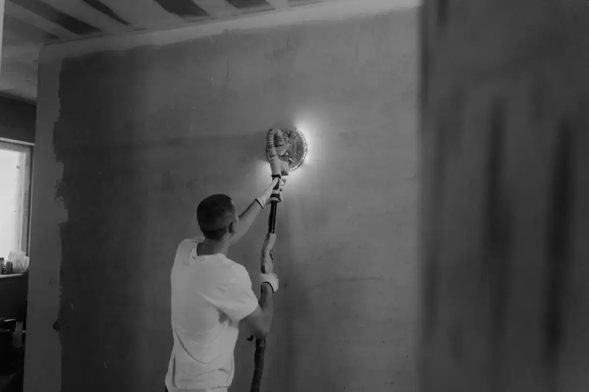 Power sander bringing a coated drywall surface flush during finishing work in Davenport
