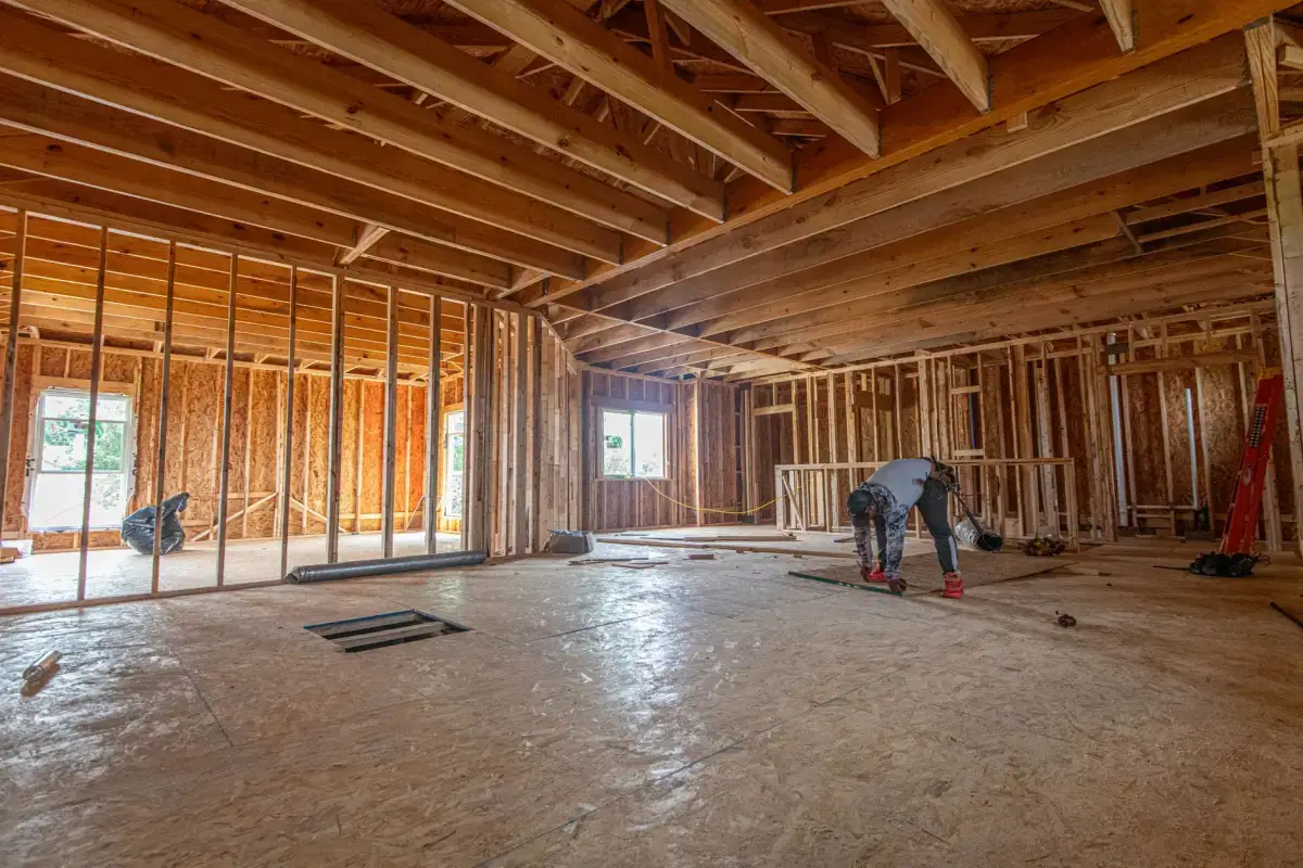 Open stud framing and roof trusses in a house interior at the stage just before drywall goes up