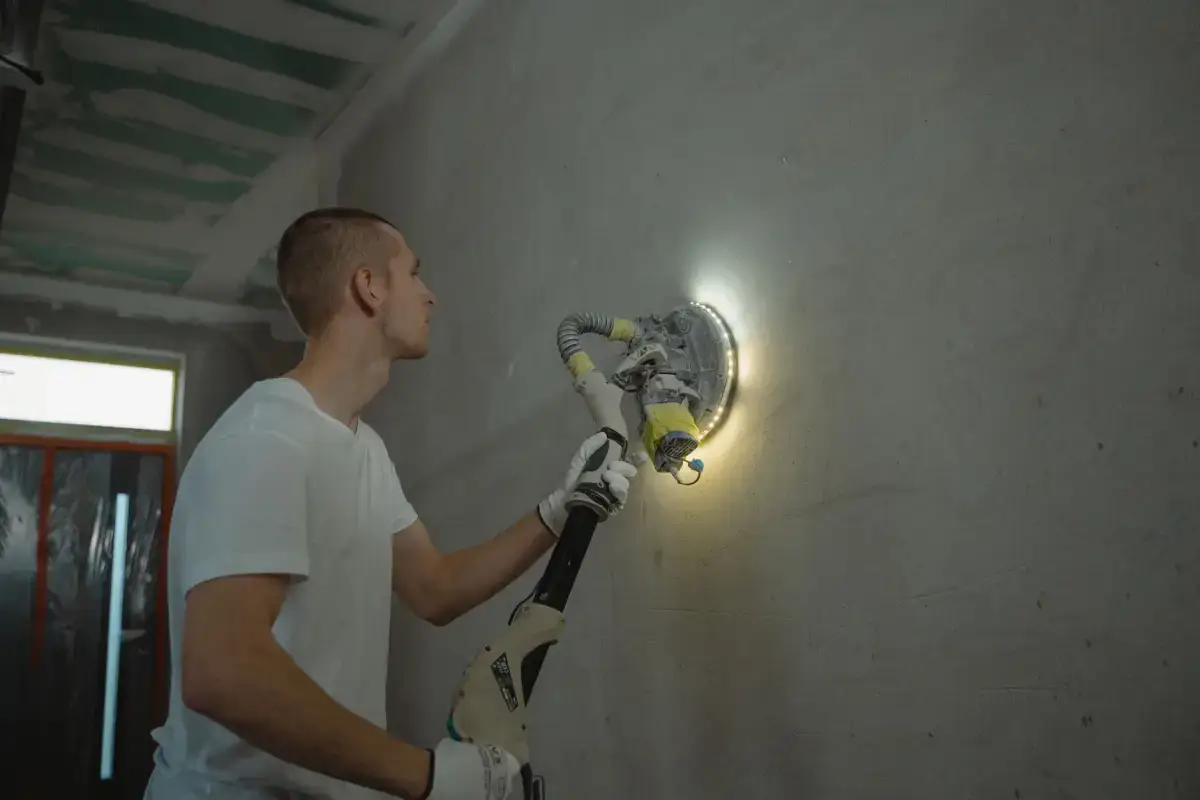 Sanding block feathering the edges of a drywall patch out into the surrounding wall