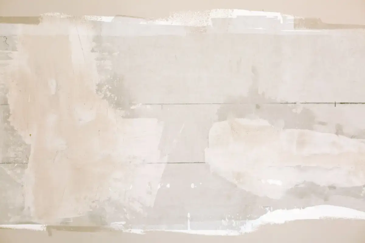 Unfinished drywall patch showing compound built up over a repaired section before sanding