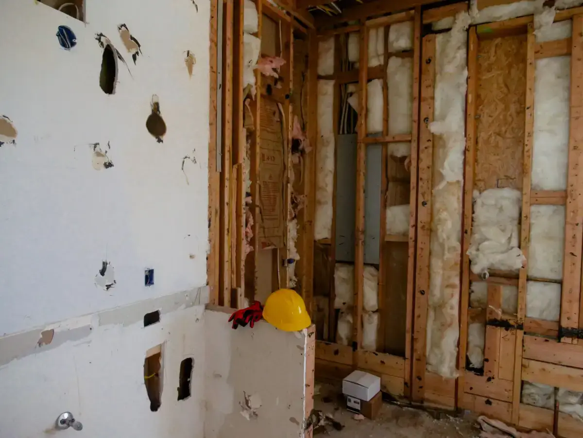 Damaged drywall partly removed from a wall, exposing stud framing and insulation during a Davenport drywall replacement