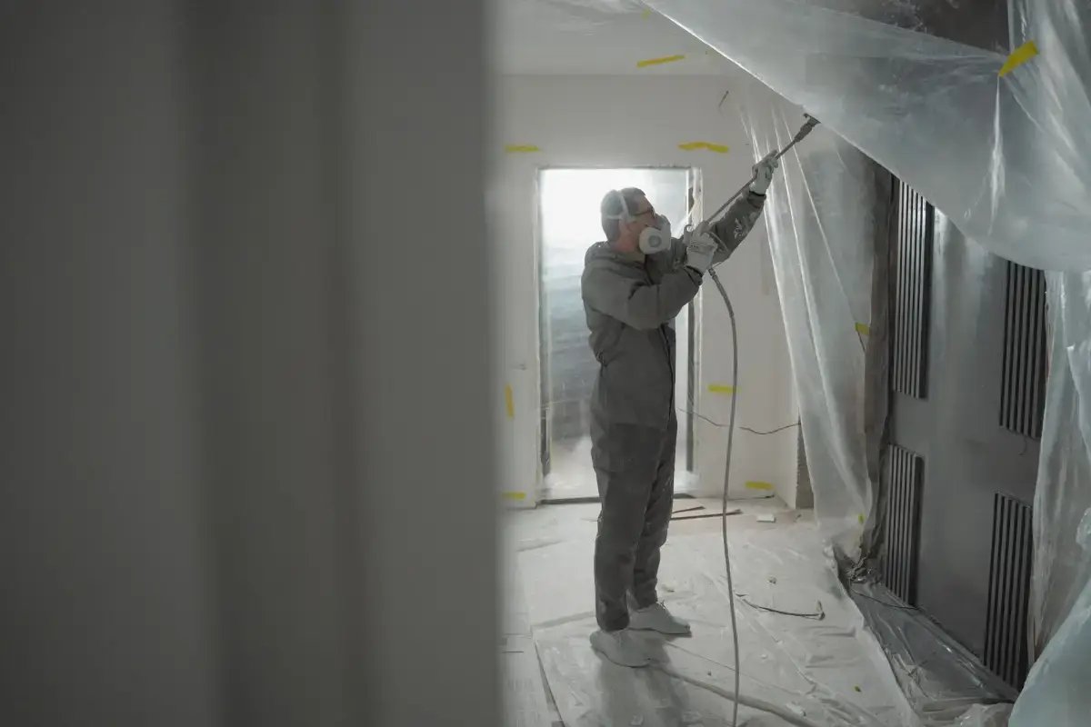 Texture being sprayed with the operator in protective gear and the surrounding area masked off