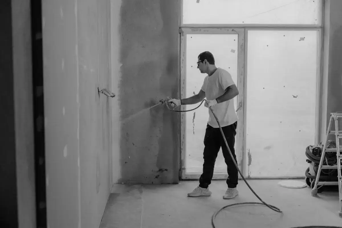 Texture compound being sprayed onto a wall through a hopper gun on a Davenport drywall texturing job